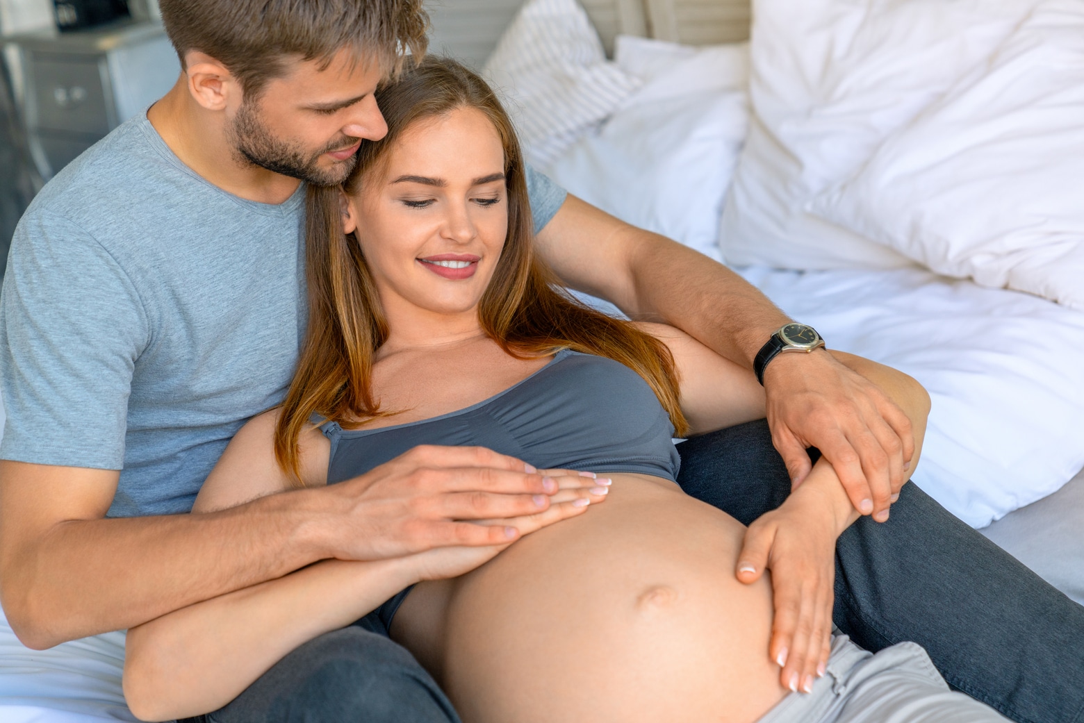 couple with pregnant woman relaxing on sofa together