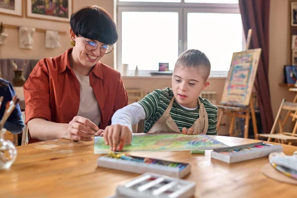 boy with down syndrome enjoying art class with teacher