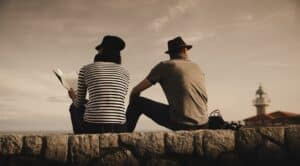 man and woman on stones near lighthouse